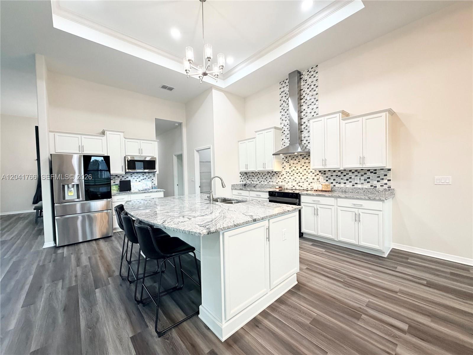 7041 Northeast 22nd Ct Road Ocala, FL 34479 - Photo 26 of 55 a kitchen with stainless steel appliances kitchen island granite countertop a sink cabinets and wooden floor