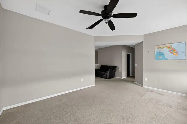 an empty room with ceiling fan and windows