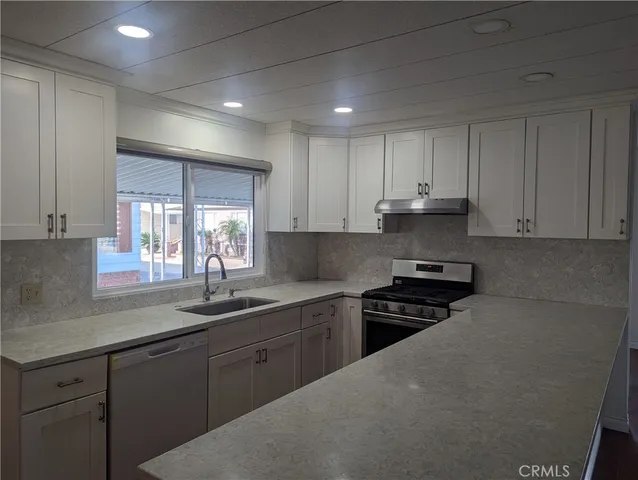 a kitchen with cabinets appliances a sink and a window
