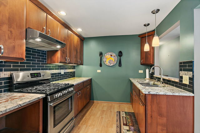 1871 Fox Run Drive, Unit A Elk Grove Village, IL 60007 - Photo 10 of 27 a kitchen with stainless steel appliances granite countertop a stove a sink and a microwave
