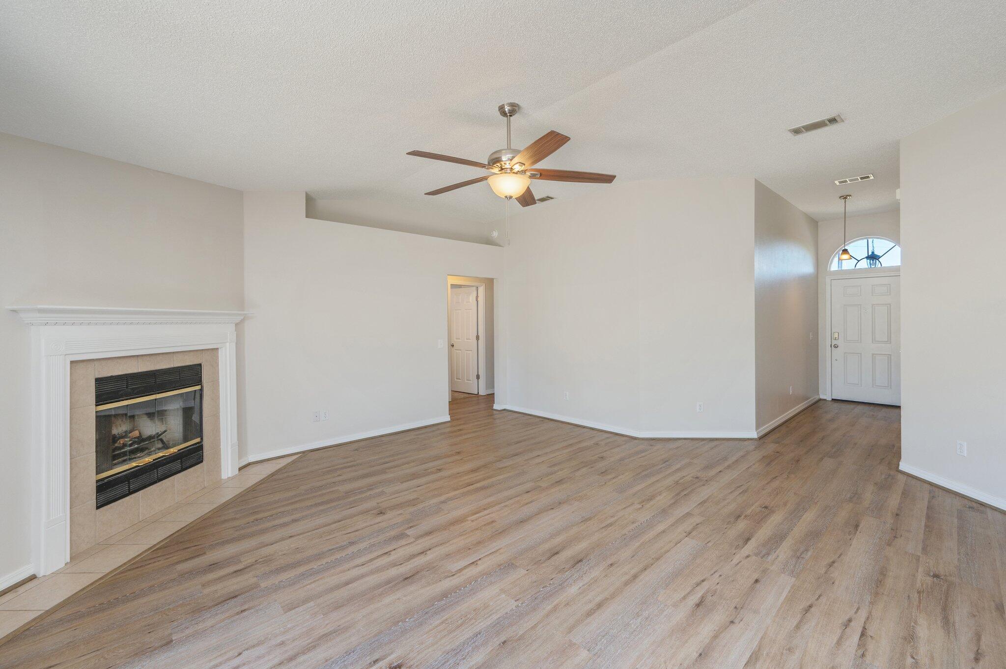 459 Jillian Drive Crestview, FL 32536 - Photo 7 of 46 an empty room with wooden floor a chandelier fan and windows