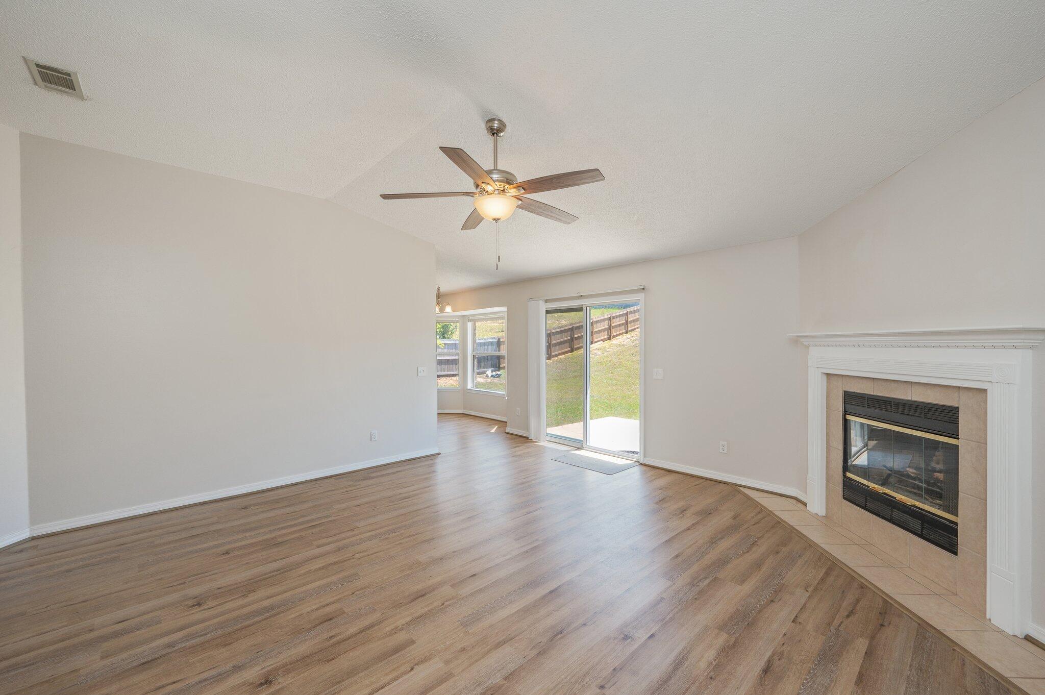 459 Jillian Drive Crestview, FL 32536 - Photo 9 of 46 an empty room with wooden floor fireplace and a ceiling fan