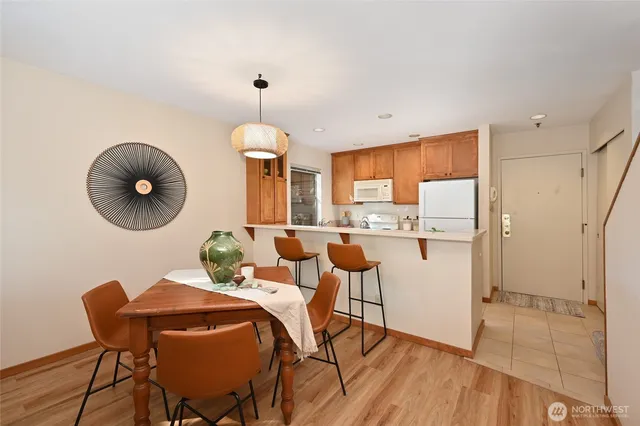 a kitchen with a refrigerator a stove a sink and a dining table with wooden cabinet