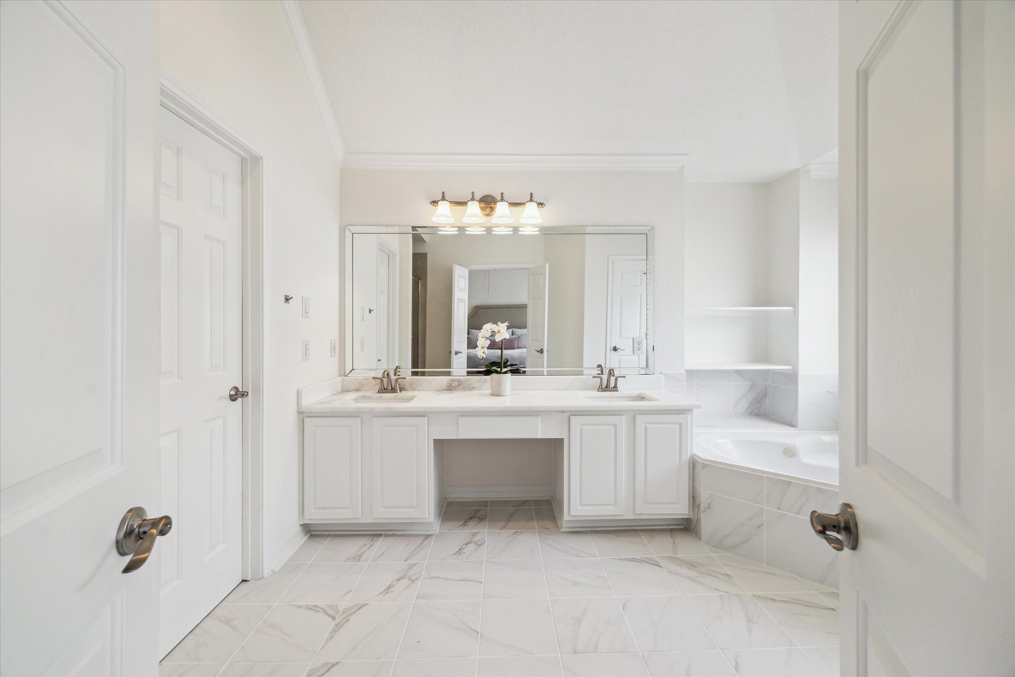 909 Reinicke Street Houston, TX 77007 - Photo 12 of 19 Primary bathroom features a dual-sink vanity, fresh flooring, updated countertops, new plumbing fixtures, and exquisite tiling adorning the jetted tub, resulting in a decadent, revitalized spa-like atmosphere.