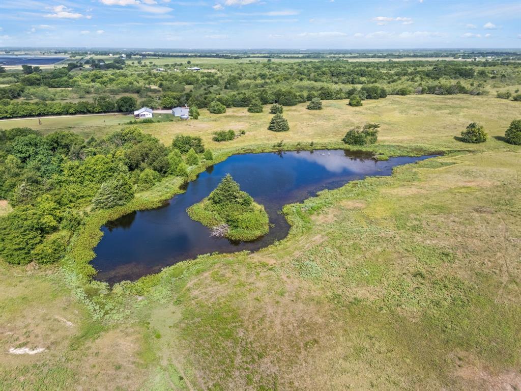 0 Fm Road Kaufman, TX 75142 - Photo 4 of 13 Expansive rural landscape featuring a prominent pond with an island, surrounded by natural grasslands and mature trees