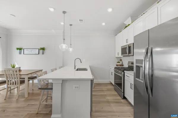 a kitchen with stainless steel appliances kitchen island granite countertop a refrigerator a stove a sink with a dining table and chairs