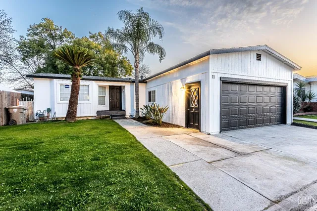 a front view of house with yard and trees in the background