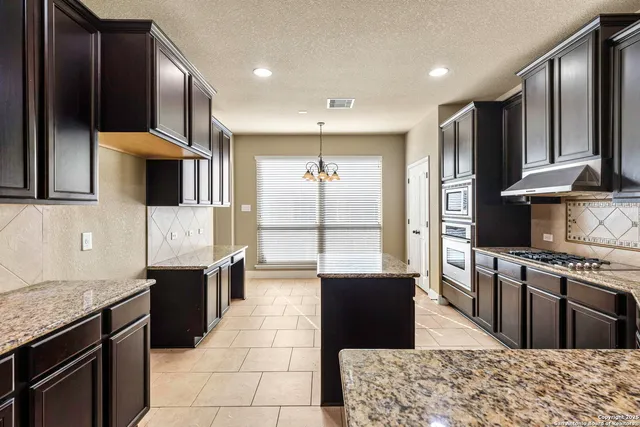 a kitchen with stainless steel appliances granite countertop a stove top oven a sink and a refrigerator