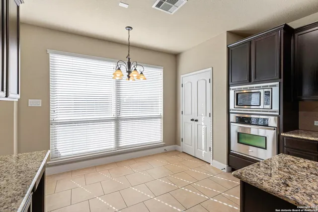 a view of kitchen with granite countertop cabinets and refrigerator