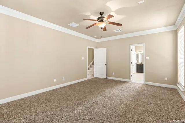 an empty room with chandelier fan and windows