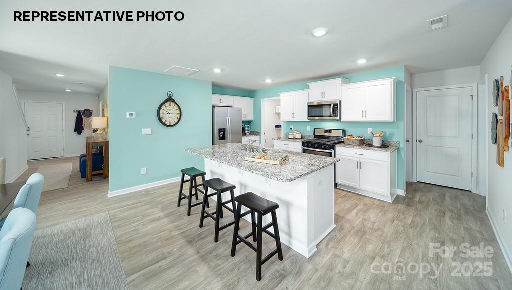 834 North Naughton Street Chester, SC 29706 - Photo 5 of 28 a kitchen with stainless steel appliances kitchen island granite countertop a stove a sink a microwave a refrigerator and white cabinets with wooden floor