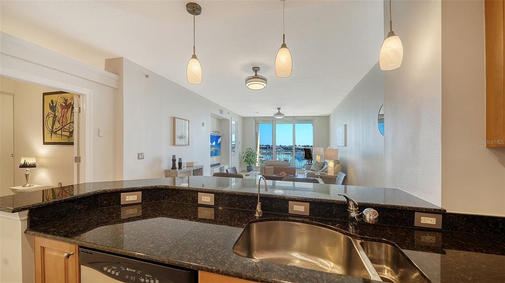 610 Riviera Dunes Way, Unit 306 Palmetto, FL 34221 - Photo 10 of 58 a kitchen with granite countertop a sink a counter top space and living room view