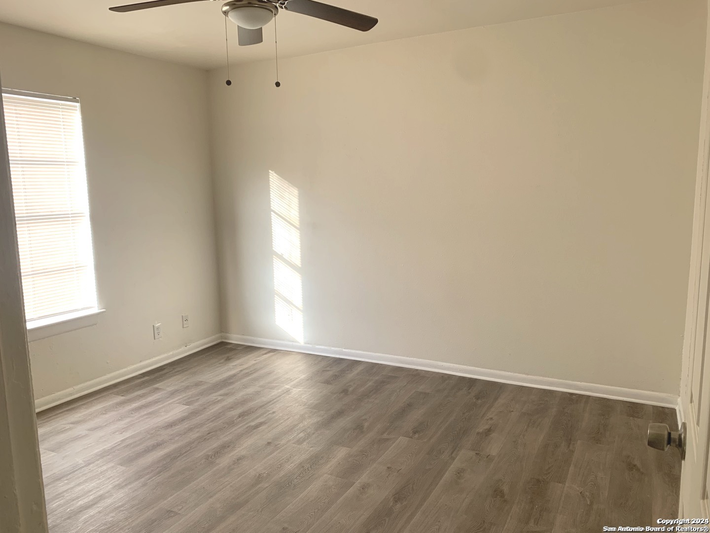 3915 Sherril Brook Road, Unit 4 San Antonio, TX 78228 - Photo 4 of 6 a view of an empty room with wooden floor and a window