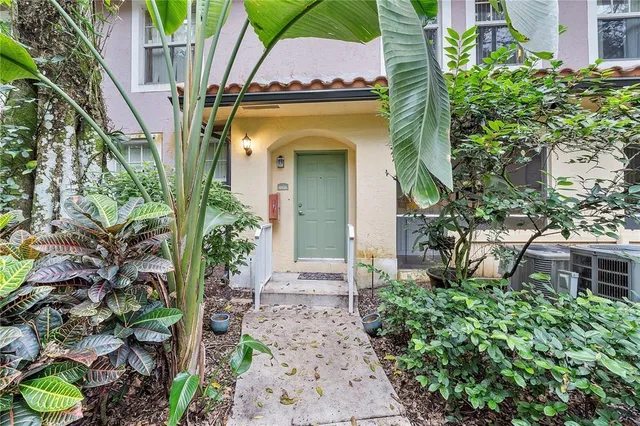 a view of a house with a small yard plants and large tree