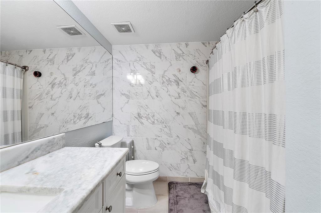 6926 West Sample Road, Unit 6926 Coral Springs, FL 33067 - Photo 23 of 41 a bathroom with a granite countertop toilet sink and shower