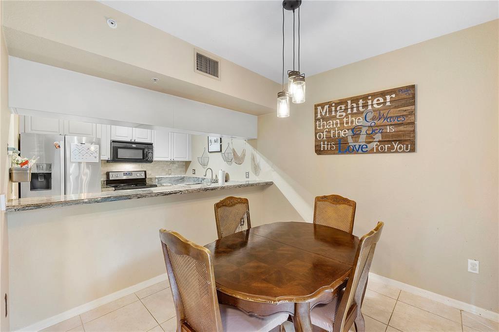 6926 West Sample Road, Unit 6926 Coral Springs, FL 33067 - Photo 8 of 41 a kitchen with stainless steel appliances granite countertop a dining table chairs and a refrigerator