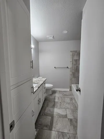 a bathroom with a granite countertop sink a toilet and shower
