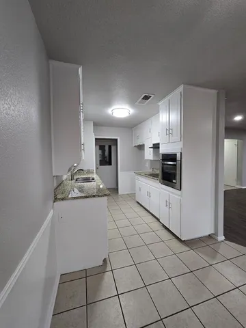 a large white kitchen with a stove a sink a microwave and cabinets