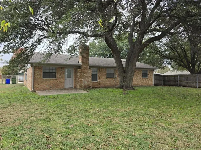 a view of a yard in front of a house with large trees
