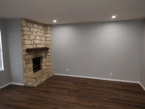 a view of a livingroom with wooden floor and a fireplace