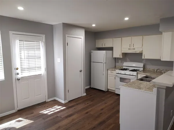 a kitchen with a refrigerator a stove top oven and cabinets