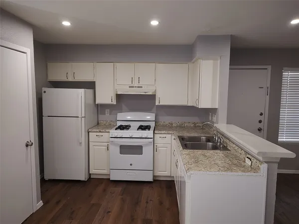 a kitchen with a stove a refrigerator and white cabinets
