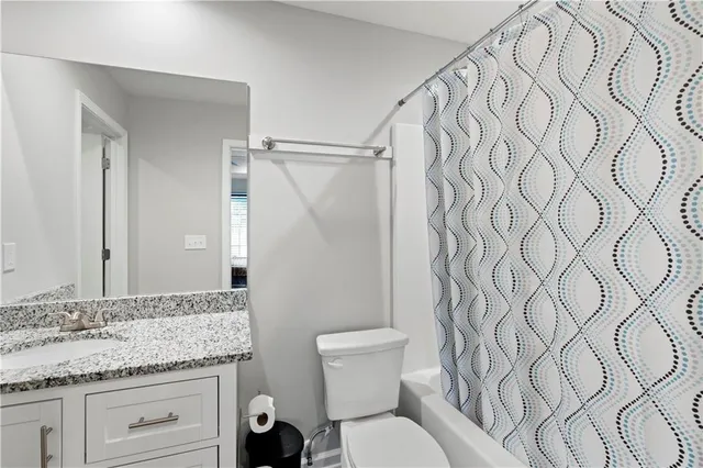 a bathroom with a granite countertop sink and a toilet