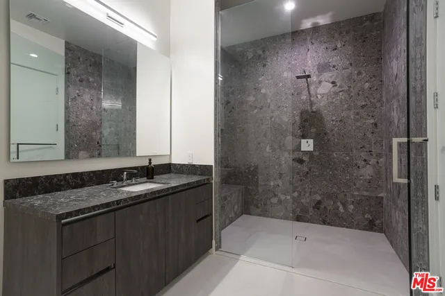 a bathroom with a granite countertop sink mirror and shower