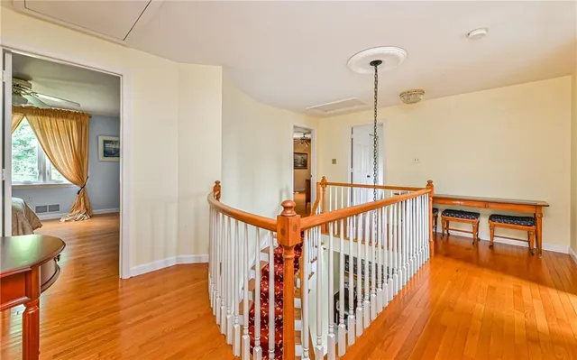 a view of a hallway with wooden floor stairs and a living room