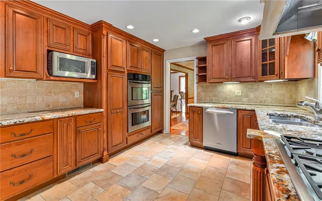 a kitchen with stainless steel appliances granite countertop a refrigerator stove top oven and sink