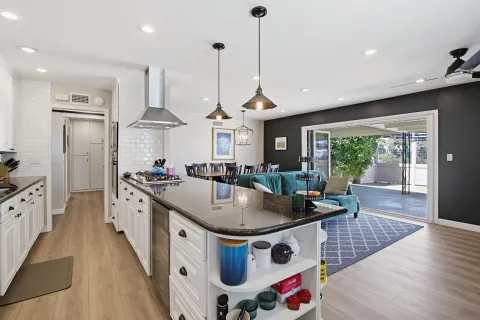 a kitchen with stainless steel appliances granite countertop a sink a stove and a wooden floor