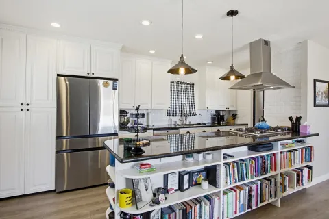 a kitchen with stainless steel appliances granite countertop a refrigerator a stove and a wooden floors