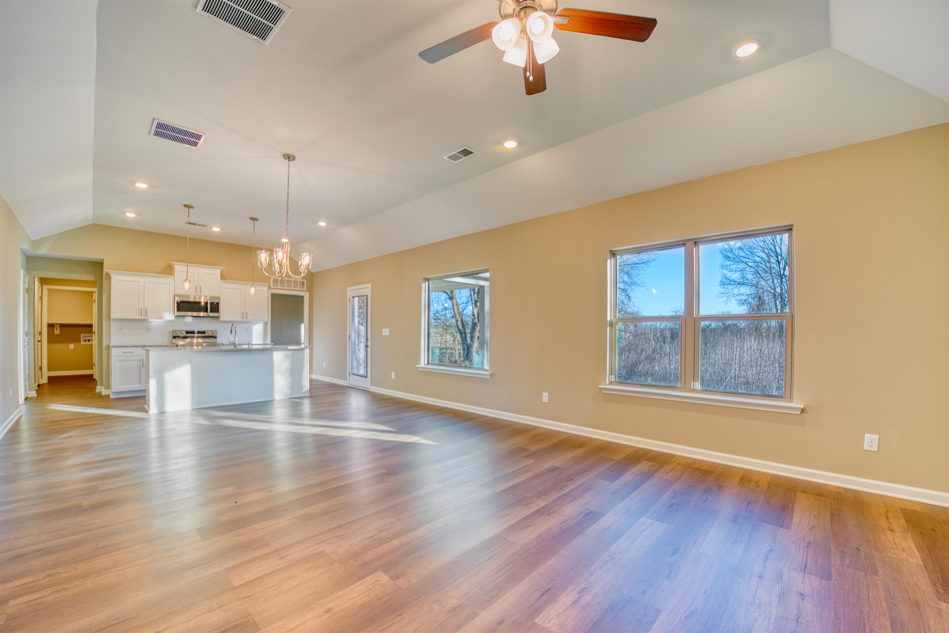 107 Stone Brook Cove Ripley, TN 38063 - Photo 19 of 31 an empty room with wooden floor a ceiling fan and kitchen view