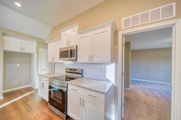 a kitchen with stainless steel appliances granite countertop a sink a stove and a microwave oven with cabinets
