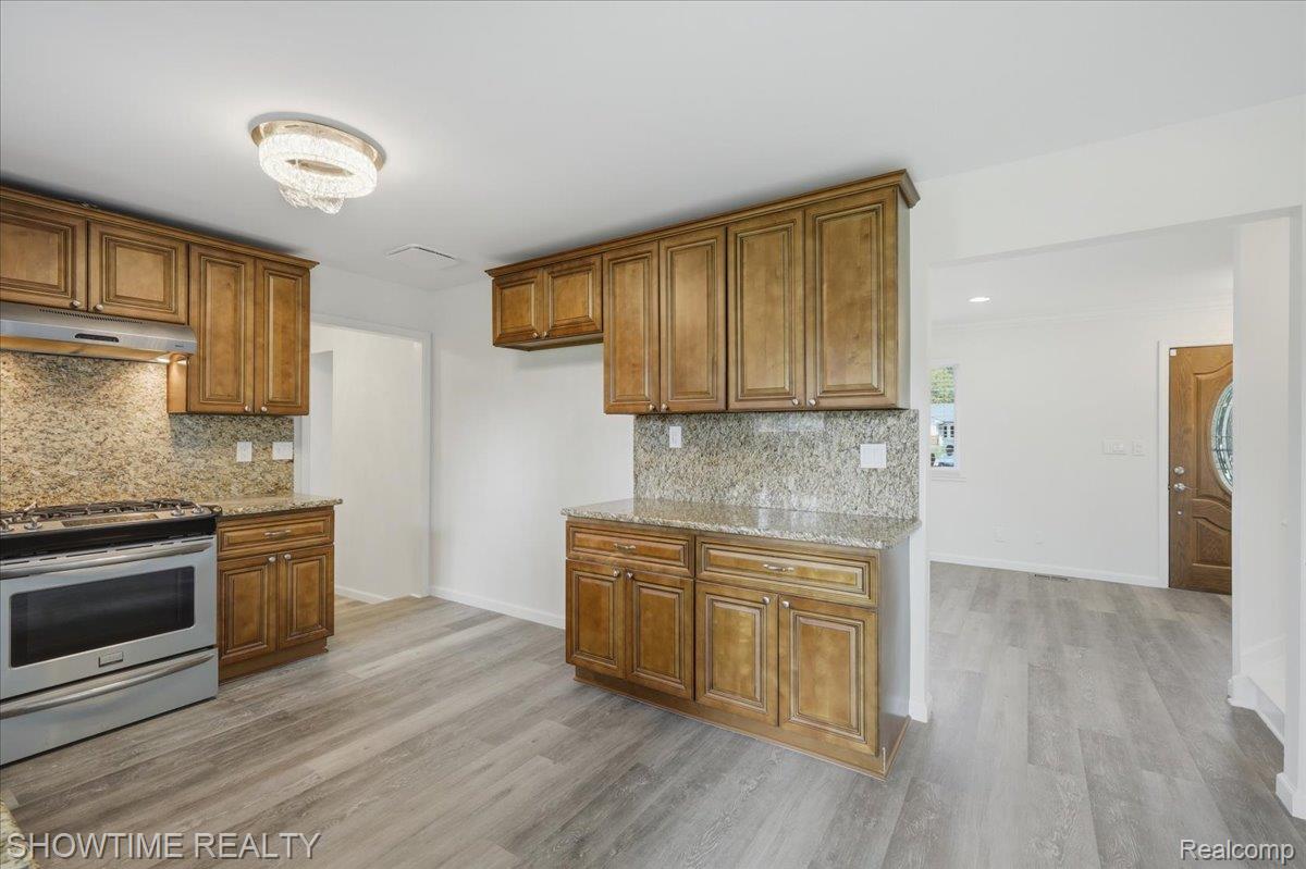 29255 Utley Road Farmington, MI 48334 - Photo 15 of 46 Kitchen featuring wood cabinetry, stone countertops, stainless steel range with hood, stone backsplash, and wood-finish flooring