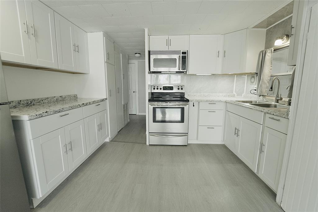 8520 Southwest 18th Court Davie, FL 33324 - Photo 10 of 48 a kitchen with stainless steel appliances granite countertop a stove a sink and white cabinets