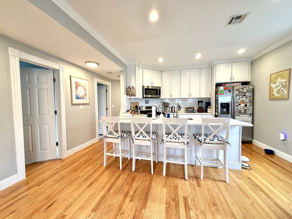 37 Moseley Street, Unit 3 Boston, MA 02125 - Photo 2 of 17 a kitchen with stainless steel appliances granite countertop a dining table chairs refrigerator and sink