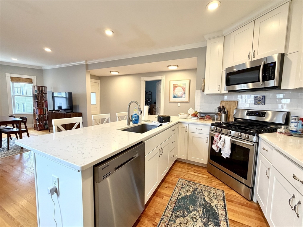 37 Moseley Street, Unit 3 Boston, MA 02125 - Photo 4 of 17 a kitchen with stainless steel appliances granite countertop a sink and dishwasher a stove top oven with wooden floor
