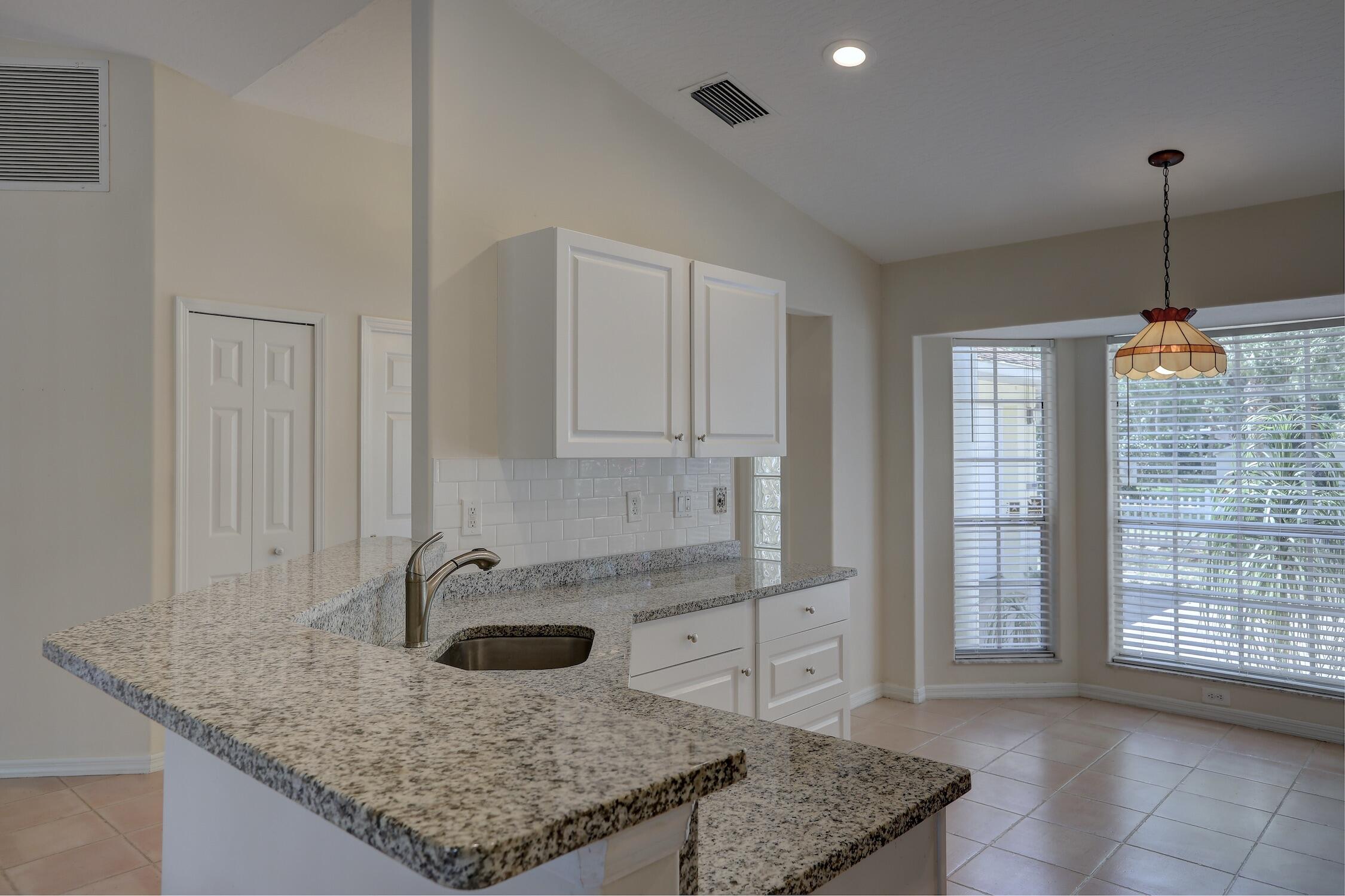 1245 George Street Sebastian, FL 32958 - Photo 23 of 36 a kitchen with kitchen island granite countertop a sink a counter top space and cabinets