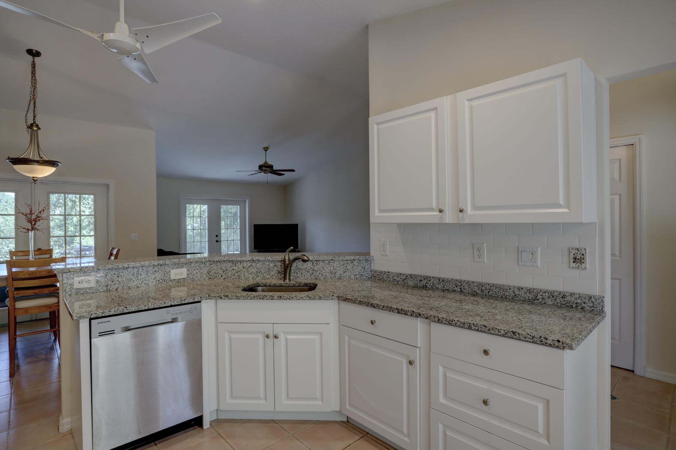 1245 George Street Sebastian, FL 32958 - Photo 25 of 36 a kitchen with granite countertop white cabinets and white appliances