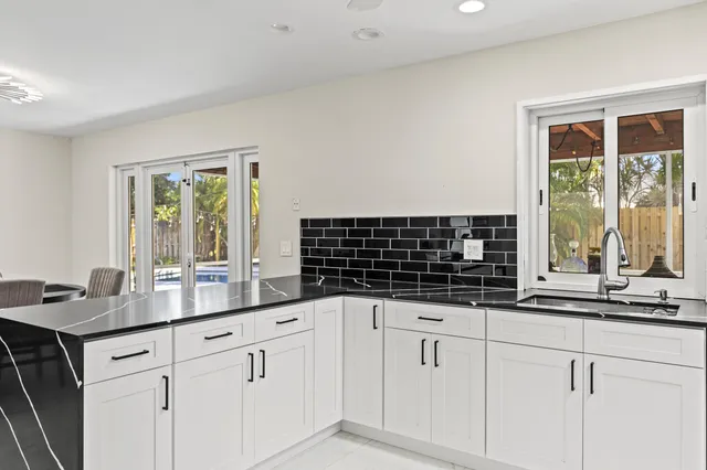 a kitchen with granite countertop white cabinets and a window