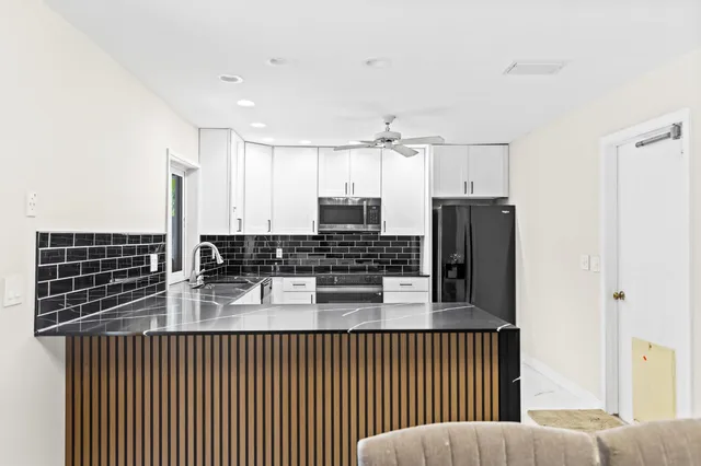 a kitchen with kitchen island granite countertop a refrigerator and a sink