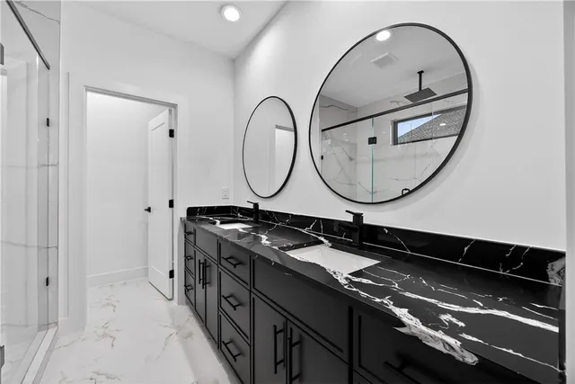 a spacious bathroom with a granite countertop sink a mirror and shower