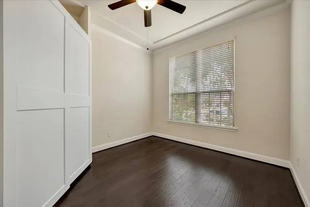 an empty room with wooden floor chandelier fan and windows