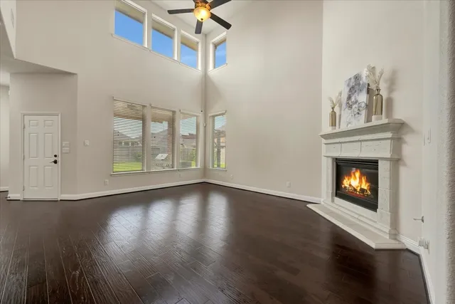 a view of an empty room with wooden floor fireplace and a window