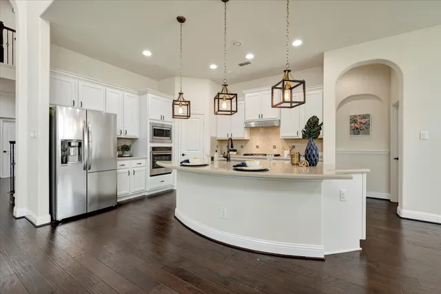 a kitchen with stainless steel appliances granite countertop a refrigerator and a stove top oven