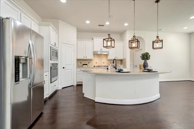 a kitchen with kitchen island stainless steel appliances a refrigerator sink and white cabinets