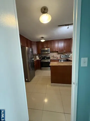 a kitchen with kitchen island wooden cabinets a refrigerator stove a sink and dishwasher