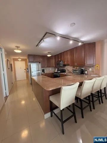 a kitchen with stainless steel appliances kitchen island granite countertop a table chairs sink and cabinets