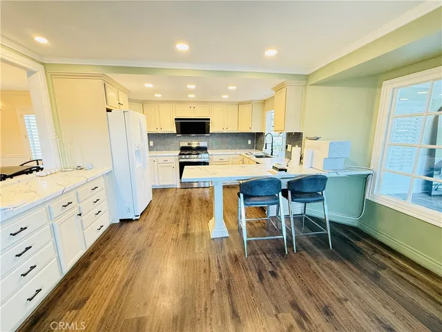 a large dining hall with stainless steel appliances granite countertop a stove oven a flat screen tv and a refrigerator